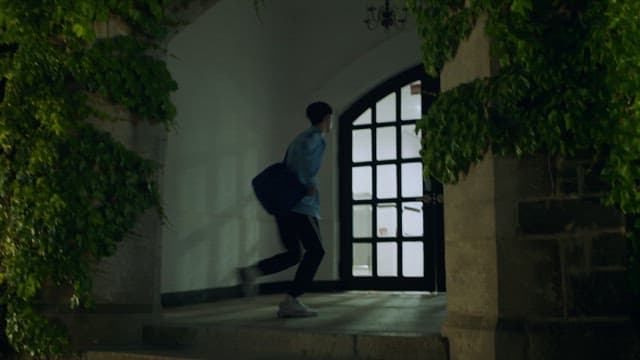 Man running into building covered by ivy at night