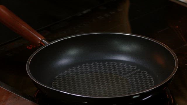 Pork being fried in an oiled frying pan