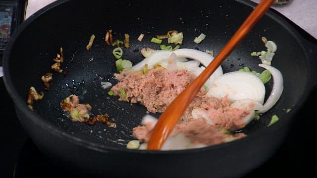 Frying the onions and tuna in a hot skillet