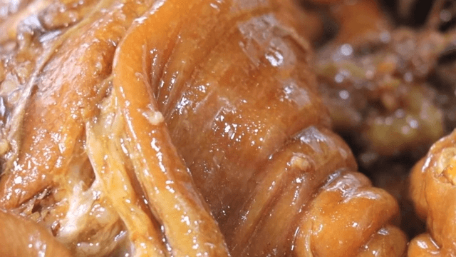 Cooking process of simmered pig's feet with gloved hands