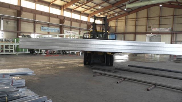 Forklift moving metal sheets in a factory