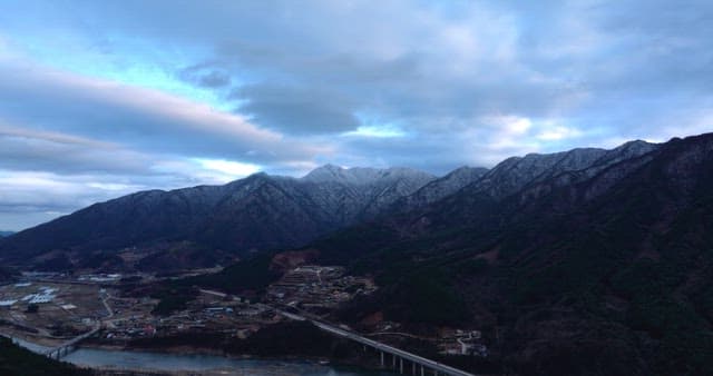 Suburban village between mountains under cloudy blue sky