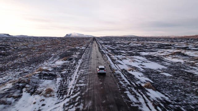 Car driving on a snowy road in a vast landscape
