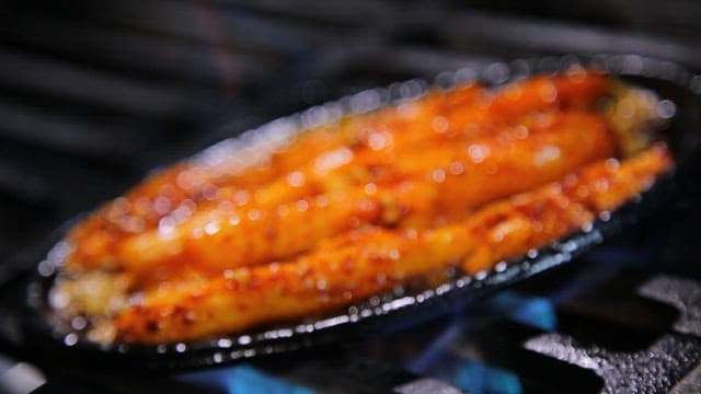 Spicy seasoned grilled deodeok cooked on a hot iron plate