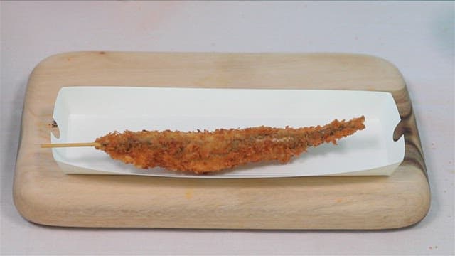 Crispy fried sand eels skewers on a wooden cutting board