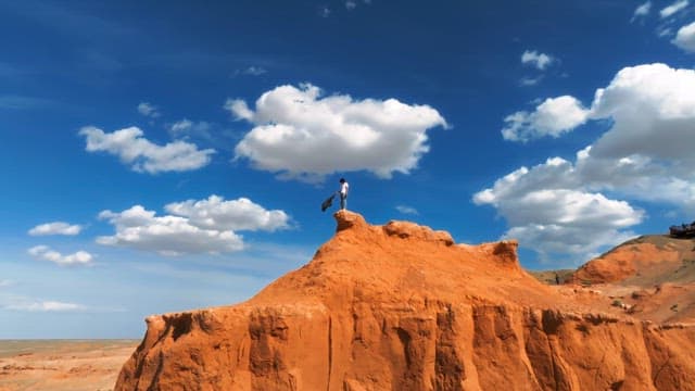 Person standing on a desert cliff under a blue sky