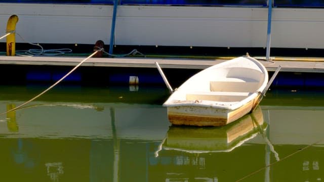 Small rowing boat tied to a dock on a calm lake.
