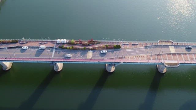 Cars driving on a bridge over a calm river
