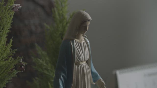 Gloved hand carefully handling a statue of the Virgin Mary