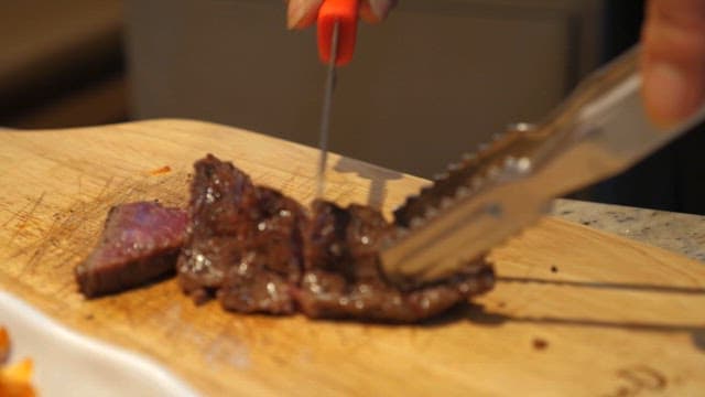 Slicing grilled steak on a cutting board