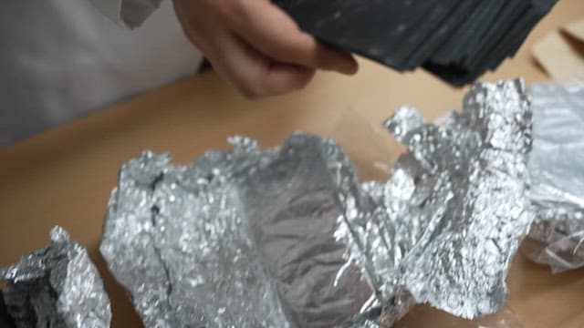 Scientist handling black samples in a lab