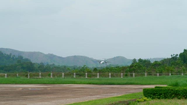 Airplane landing on a runway surrounded by hills