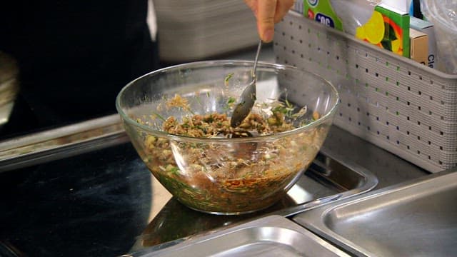 Making soy sause with wild chive by mixing ingredients in a glass bowl in the kitchen