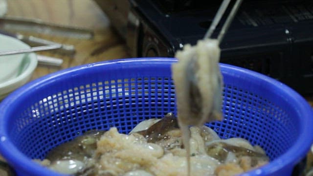 Fresh webfoot octopus being added to the boiling broth in a pot