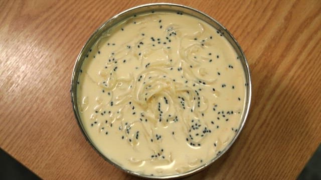 Bowl of delicious noodles in cold soybean soup on the table