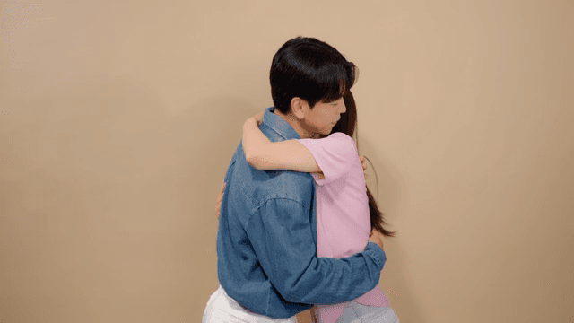 Couple embracing each other affectionately in a neutral-colored room.