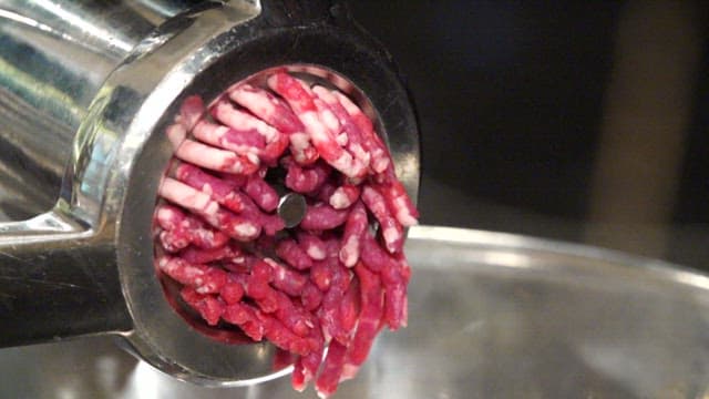 Ground beef being processed in a grinder