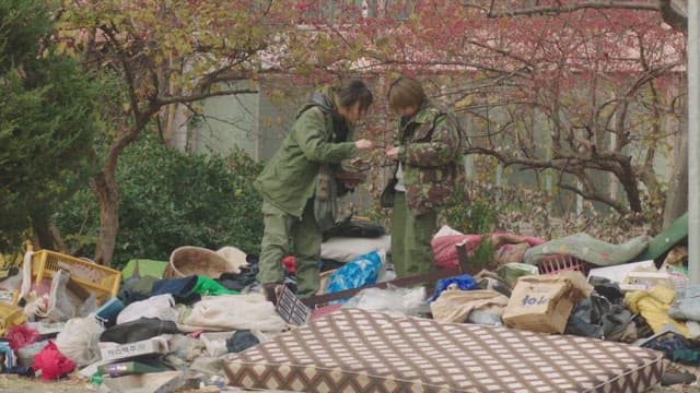 Two people looking for useful items in a dumping ground