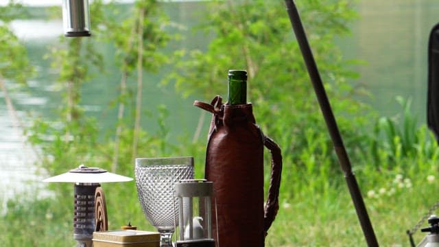 Bottle of wine and a glass on an outdoor table by the lake