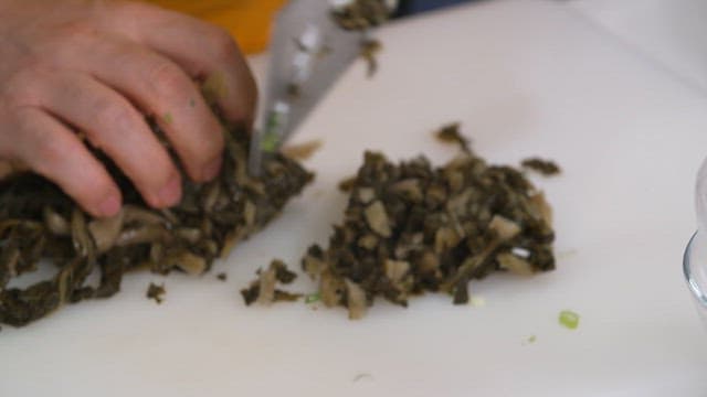 Cutting boiled dried radish greens with a knife on a cutting board