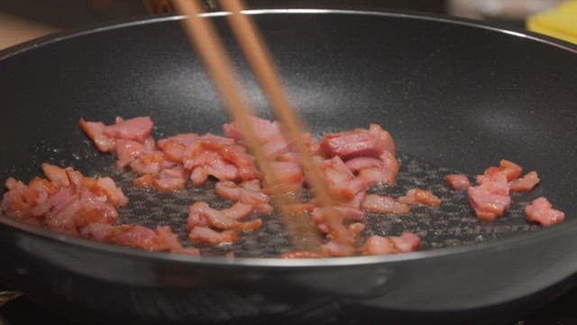 Sizzling smoked duck being stirred in a frying pan