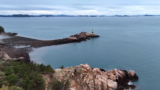 Rocky island with a yellow lighthouse in the sea
