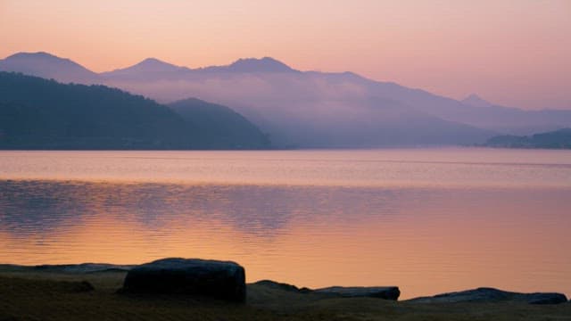 Man on the Shore of a Foggy Red Lake at Dawn