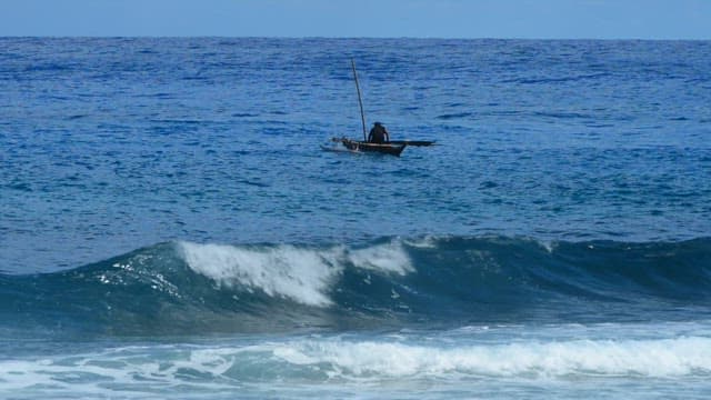 Fisherman in a small boat in the blue ocean