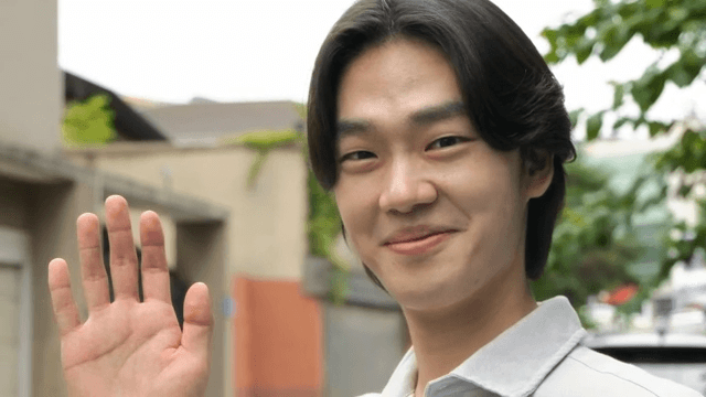 Young man smiling and waving outdoors