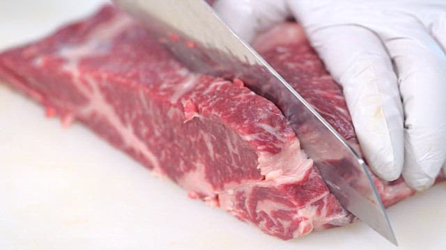 Cutting fresh steak beef on a cutting board