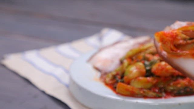 Chopstickful of Korean boiled pork with bok choy kimchi