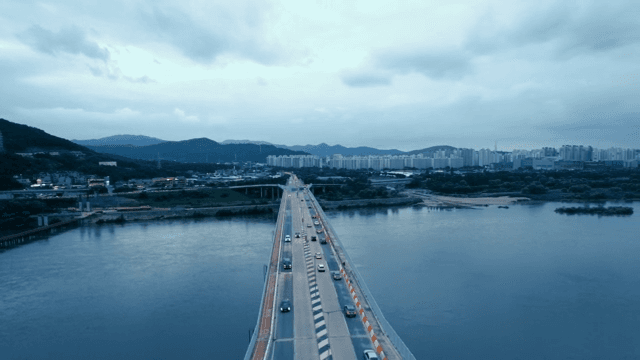 Bridge with cars passing over a river with city skyline