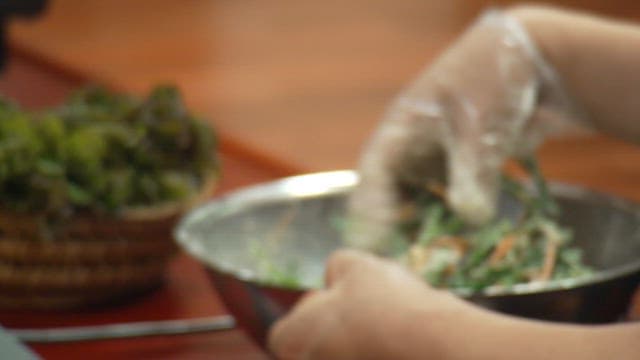 Making chive pancake batter in a stainless steel bowl with gloved hand