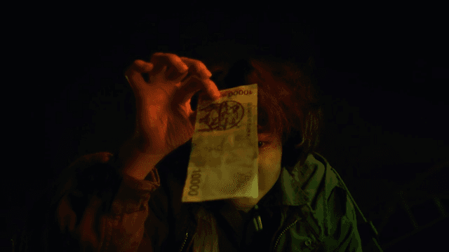 Woman picking up money from the floor at night