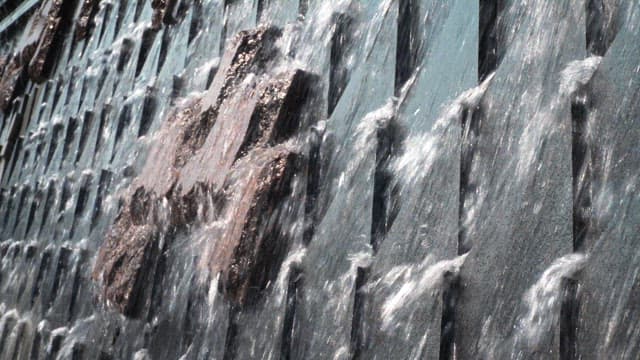 Water cascading over textured concrete wall