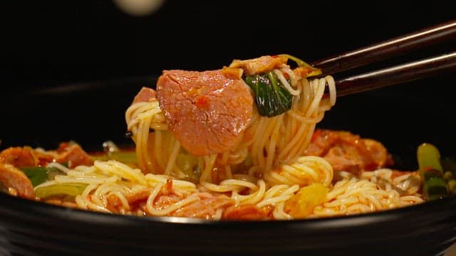 Steaming and spicy bowl of noodles with vegetables and meat