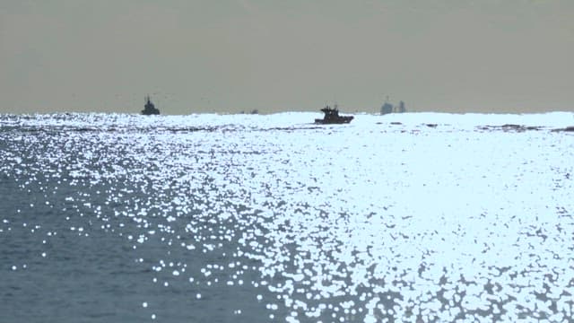 Small Boat Sailing across the Shimmering Sea during Sunset