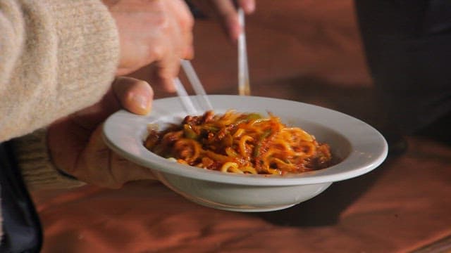 Mixing spicy Chinese meat noodles with chopsticks