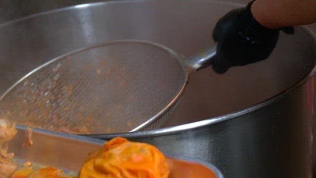 Cooking Meat using a strainer and large pot in the kitchen