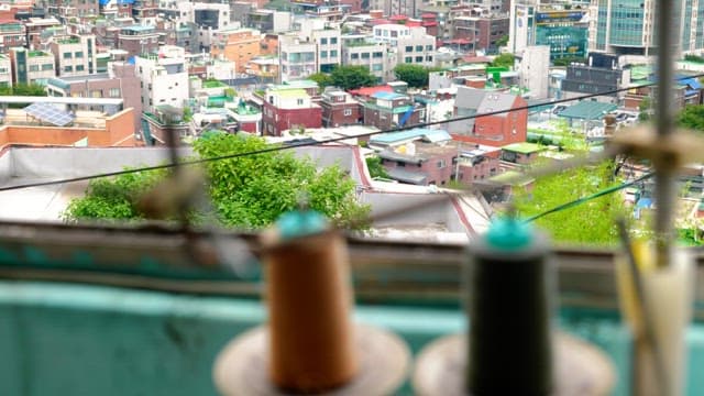 Threads from a sewing machine swaying in the wind with the city in the background