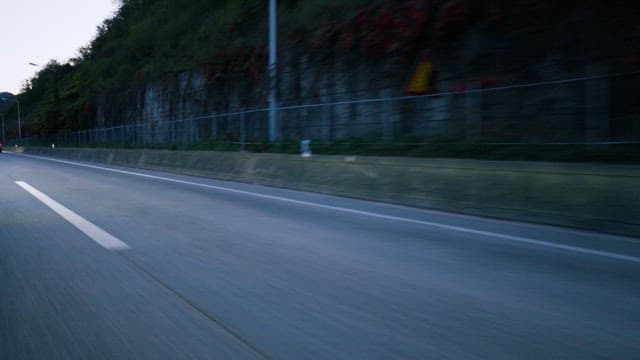 Driving past a rock wall at twilight