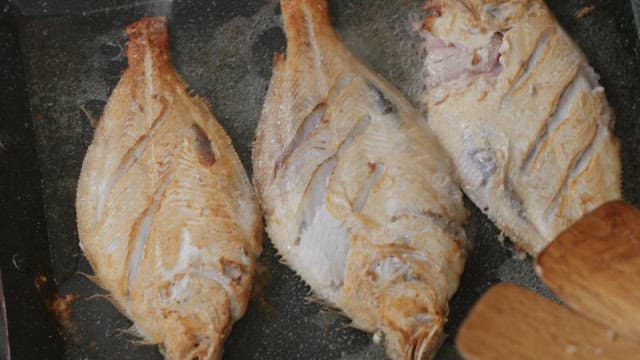 Freshly cooked fish on a hot pan being prepared