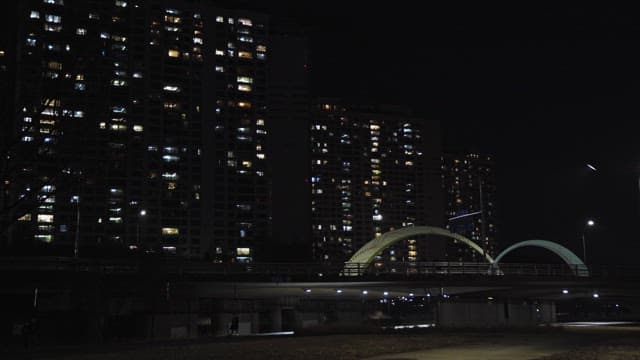 Cityscape at Night with Illuminated Buildings and Bridge