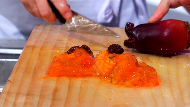 Slicing fresh sea pineapple on a wooden cutting board