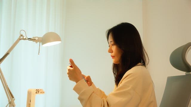 Woman using a smartphone at a desk in a calmly lit room