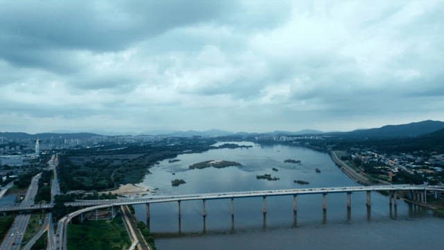 Bridge with cars passing over a river with city skyline