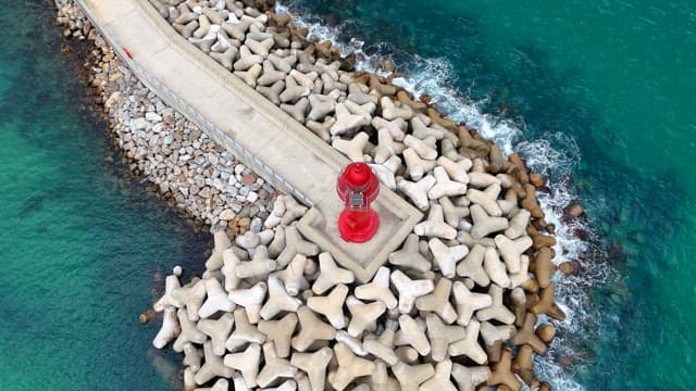 Red lighthouse on a rocky breakwater