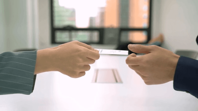Two people exchanging business cards in an office