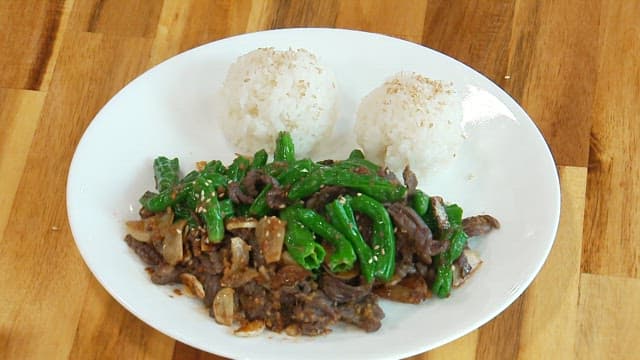 Stir-fried beef with green peppers and rice balls on a plate