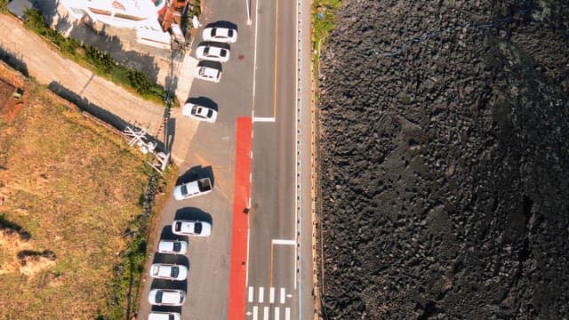 Coastal road with parked cars and rocky shore